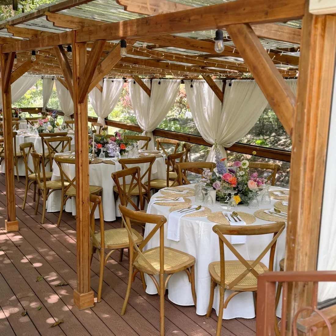 Montaje de boda bajo pérgola de madera con mesas vestidas y centros florales