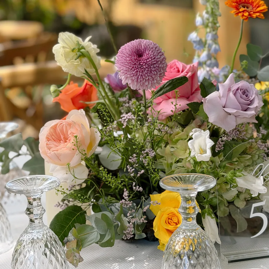 Centro de mesa con flores de colores y cristalería