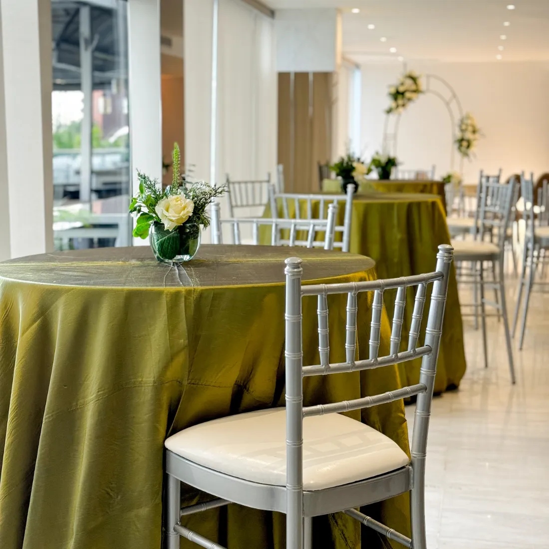 Mesas con mantelería verde oliva y sillas plateadas