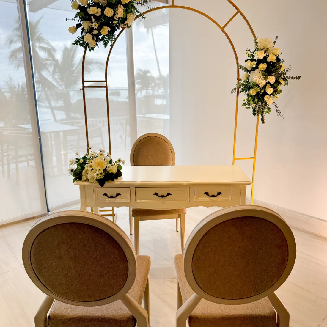 Mesa de novios con arco dorado y arreglos florales